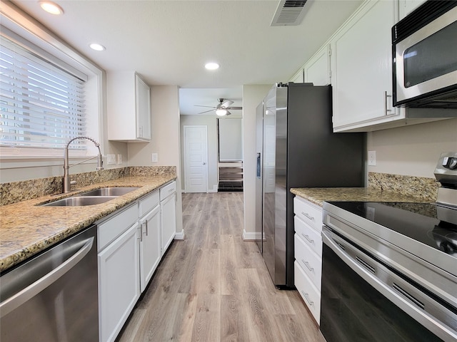 kitchen featuring visible vents, light wood-style flooring, appliances with stainless steel finishes, white cabinetry, and a sink