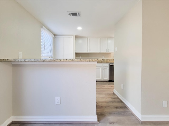 kitchen with white cabinetry, light stone counters, baseboards, and visible vents