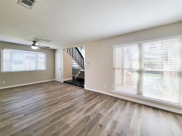 unfurnished living room with stairway, wood finished floors, visible vents, and baseboards