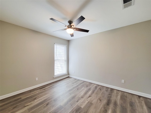 spare room with a ceiling fan, wood finished floors, baseboards, and visible vents