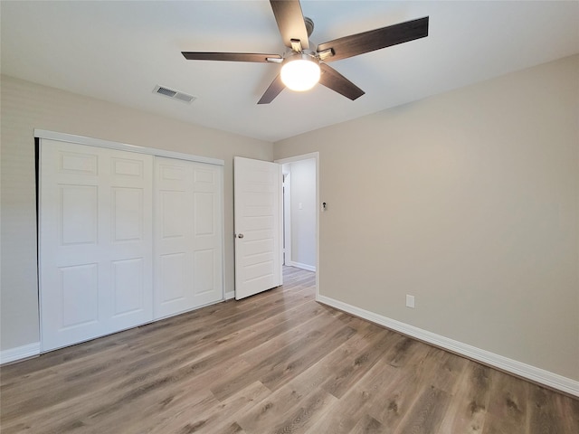 unfurnished bedroom featuring light wood finished floors, visible vents, ceiling fan, baseboards, and a closet