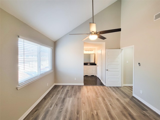 unfurnished living room featuring ceiling fan, baseboards, high vaulted ceiling, and wood finished floors