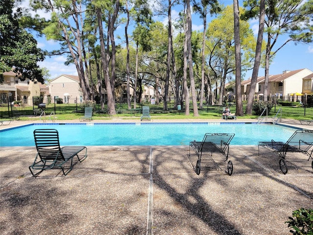 pool featuring a residential view, a patio, and fence