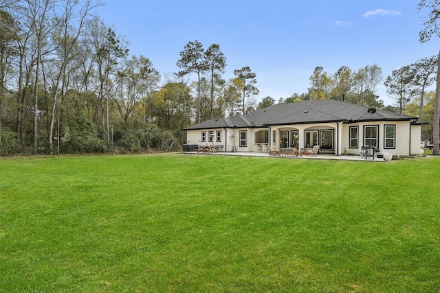 back of house with a patio area, a lawn, and a shingled roof