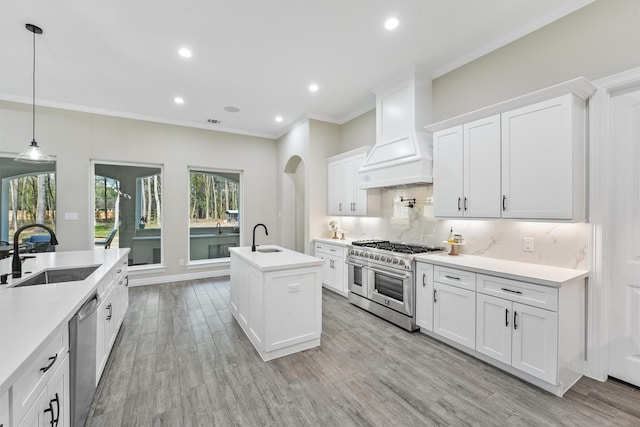 kitchen with tasteful backsplash, a center island with sink, appliances with stainless steel finishes, arched walkways, and a sink