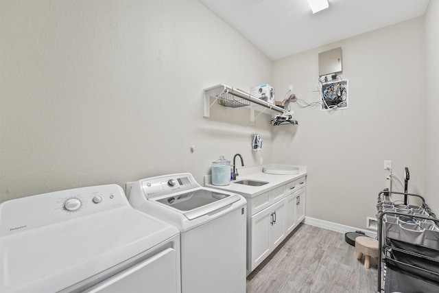 washroom with baseboards, washer and dryer, light wood-style floors, cabinet space, and a sink