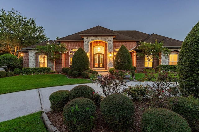 view of front of property with a front yard, french doors, and brick siding