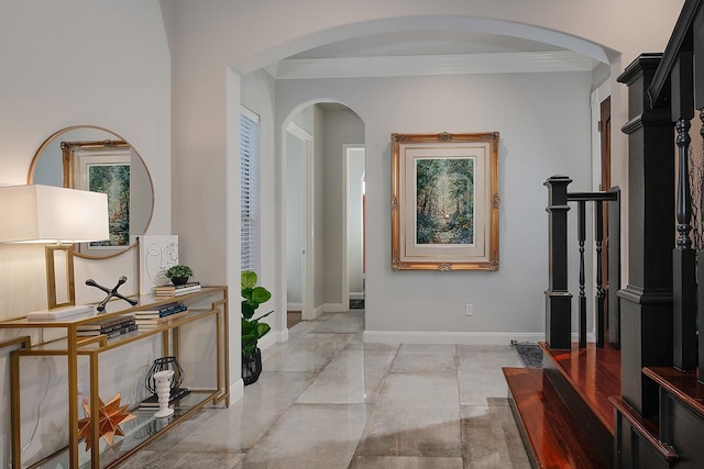 foyer entrance with arched walkways, baseboards, and ornamental molding