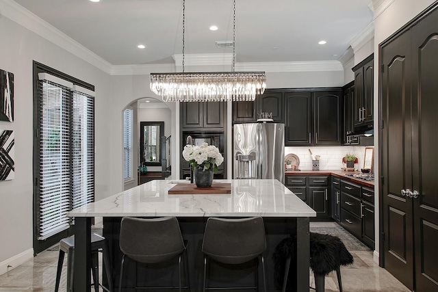 kitchen with visible vents, a kitchen island, appliances with stainless steel finishes, crown molding, and tasteful backsplash