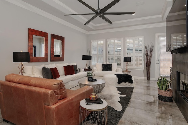 living room featuring baseboards, ceiling fan, a glass covered fireplace, crown molding, and a raised ceiling