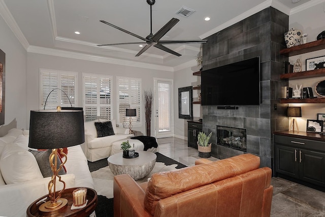 living area with a tray ceiling, visible vents, ornamental molding, and a tile fireplace