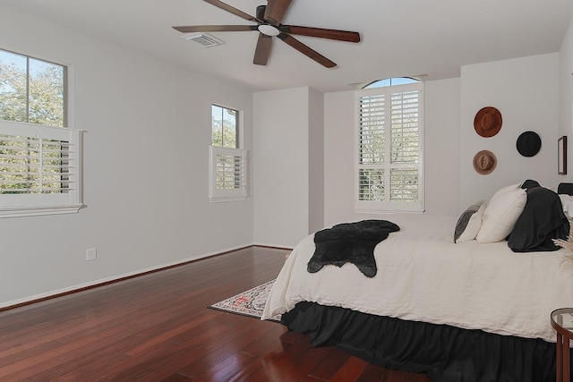 bedroom with visible vents, multiple windows, ceiling fan, and hardwood / wood-style flooring