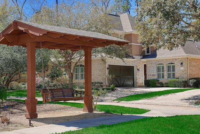 exterior space featuring stone siding, an attached garage, concrete driveway, and a shingled roof