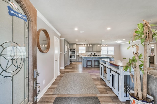 foyer with recessed lighting, baseboards, wood finished floors, and crown molding