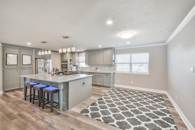 kitchen with a center island, a breakfast bar, gray cabinets, light wood-style flooring, and stainless steel appliances