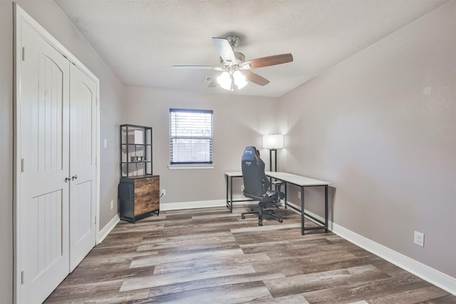 office area with a ceiling fan, wood finished floors, and baseboards