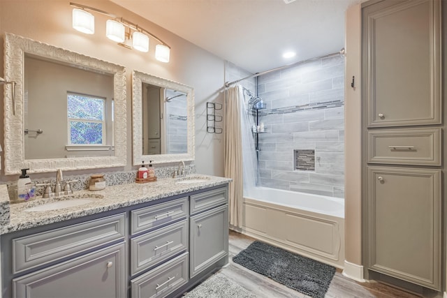 full bath with shower / bath combination with curtain, wood finished floors, double vanity, and a sink