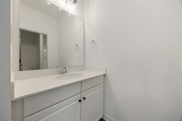 bathroom with baseboards, toilet, and vanity