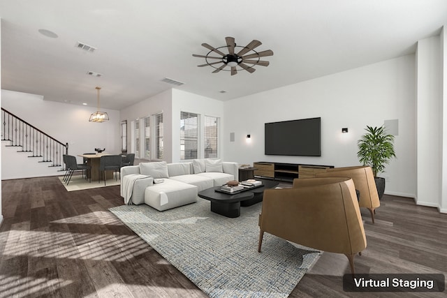 living room featuring visible vents, ceiling fan with notable chandelier, wood finished floors, and stairway