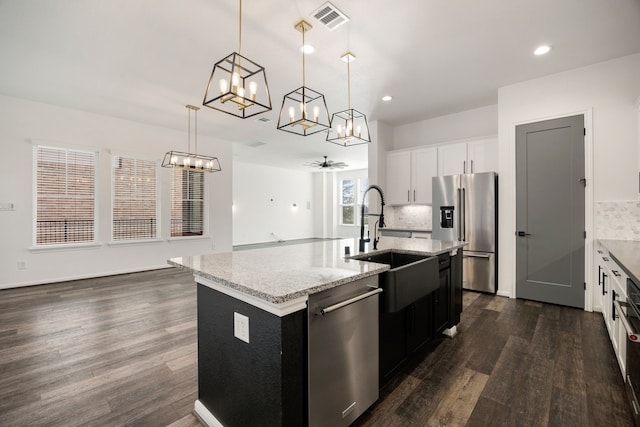 kitchen featuring visible vents, a sink, tasteful backsplash, dark wood-style floors, and appliances with stainless steel finishes