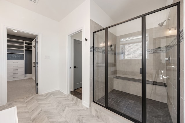 full bathroom with a shower stall, a walk in closet, and baseboards