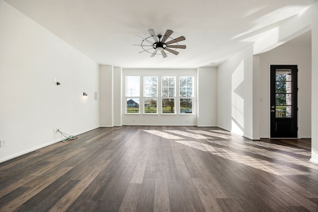 unfurnished living room with dark wood-type flooring, baseboards, and ceiling fan