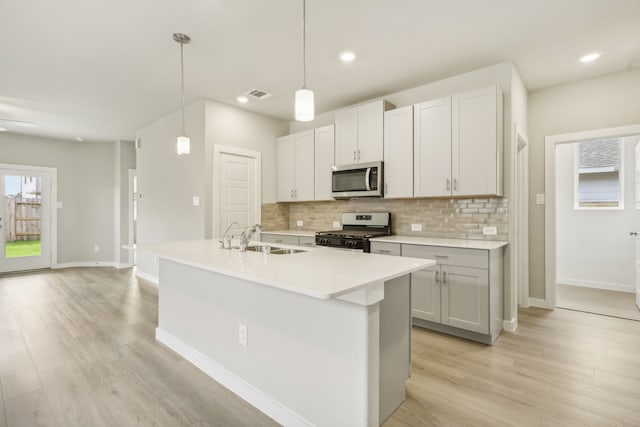 kitchen with a sink, stainless steel appliances, tasteful backsplash, and visible vents