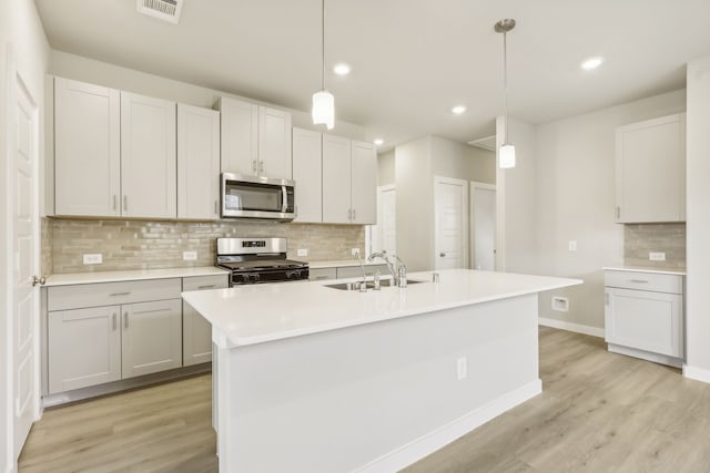 kitchen with light wood finished floors, visible vents, light countertops, appliances with stainless steel finishes, and a sink