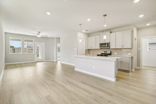 kitchen with light wood-type flooring, stainless steel appliances, tasteful backsplash, and light countertops