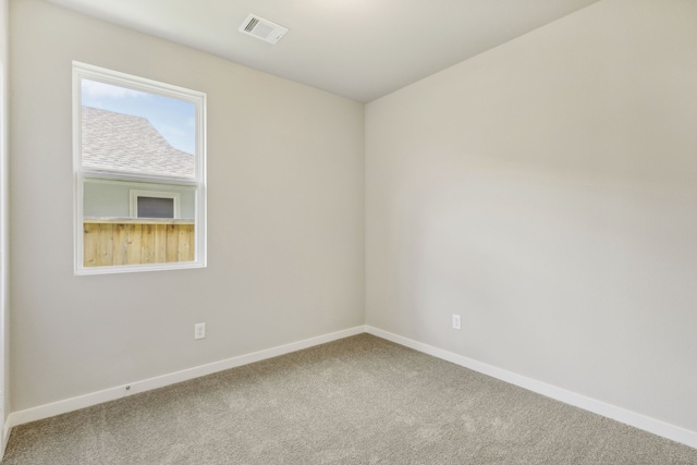 carpeted spare room featuring baseboards and visible vents