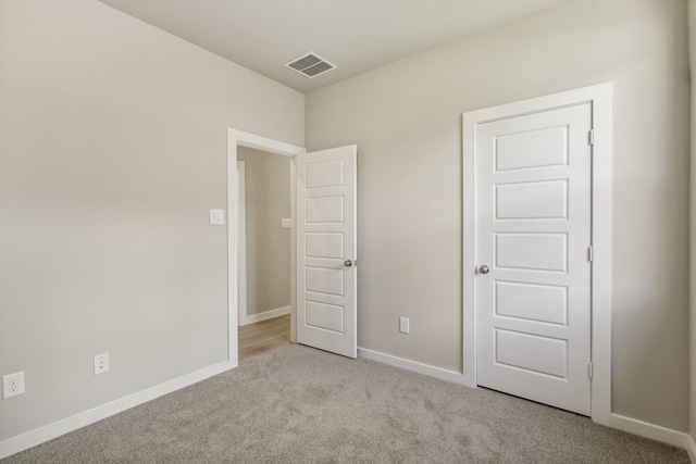 unfurnished bedroom featuring light carpet, visible vents, and baseboards