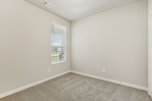 spare room featuring visible vents, light carpet, and baseboards