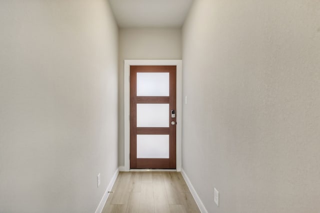 doorway with baseboards and light wood-type flooring