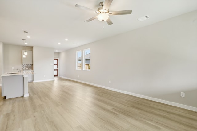 unfurnished living room with visible vents, light wood-style flooring, and baseboards