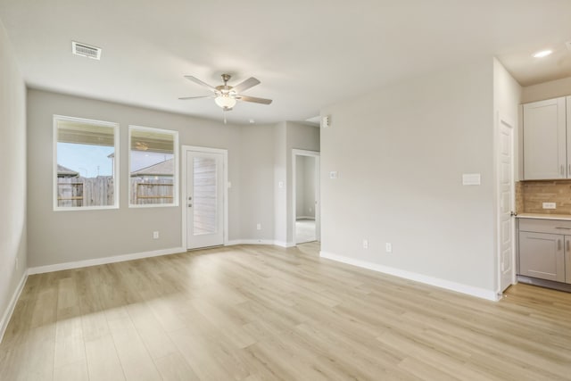 unfurnished living room with visible vents, light wood-type flooring, and baseboards