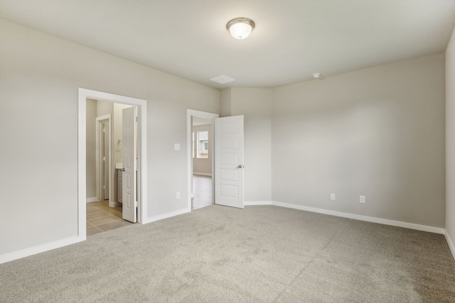 unfurnished bedroom with baseboards, ensuite bathroom, and carpet flooring