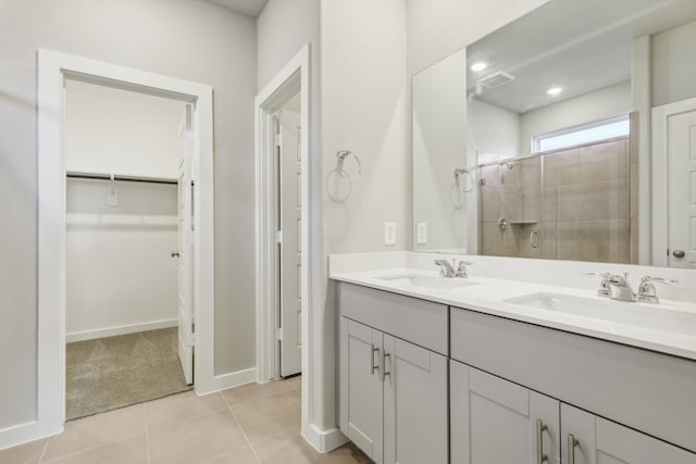 full bath featuring tile patterned flooring, a spacious closet, tiled shower, and a sink