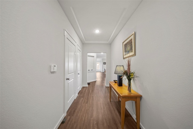 corridor with dark wood finished floors and baseboards