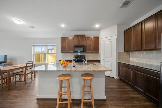 kitchen featuring visible vents, a sink, black appliances, and dark wood-style flooring