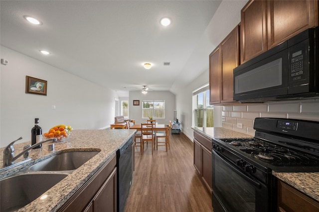 kitchen with wood finished floors, plenty of natural light, black appliances, and a sink