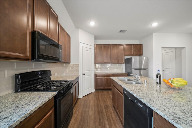 kitchen featuring visible vents, a sink, decorative backsplash, black appliances, and dark wood-style flooring