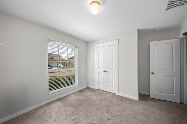 unfurnished bedroom with a closet, baseboards, visible vents, and carpet floors