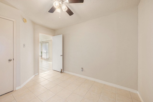 13930 Bonnercrest Dr, Houston, TX 77083 - empty room with light tile patterned floors, a ceiling fan, a smoke detector, baseboards, and a textured ceiling