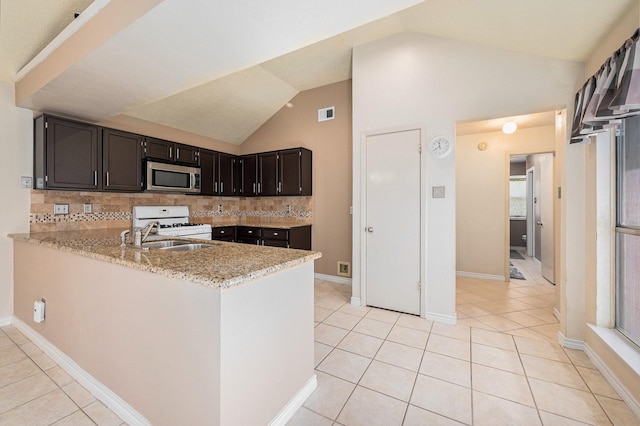 13930 Bonnercrest Dr, Houston, TX 77083 - kitchen with stainless steel microwave, white range with gas cooktop, tasteful backsplash, vaulted ceiling, and light tile patterned floors