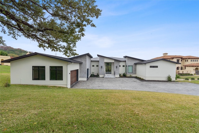 rear view of house with a lawn, stucco siding, metal roof, decorative driveway, and a standing seam roof