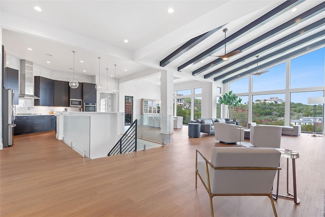 living room featuring recessed lighting, beamed ceiling, light wood-style flooring, and a towering ceiling