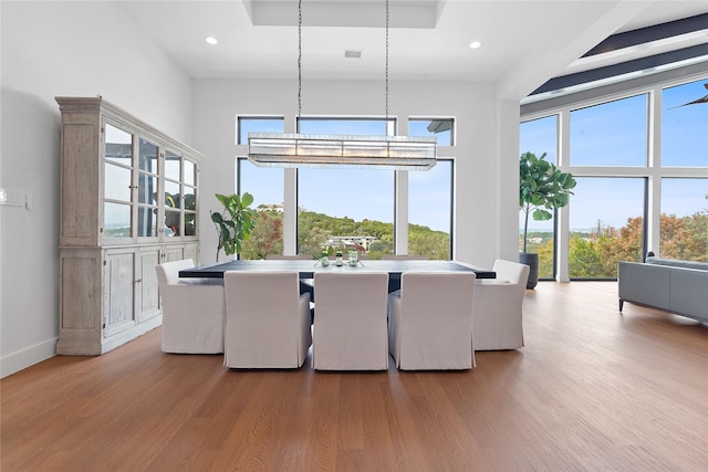 dining space featuring wood finished floors, visible vents, baseboards, recessed lighting, and a towering ceiling