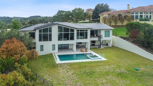 rear view of property with a patio, a yard, a fenced backyard, a pool with connected hot tub, and stucco siding