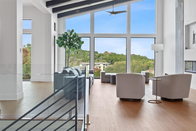 living area featuring a wealth of natural light, a towering ceiling, and wood finished floors