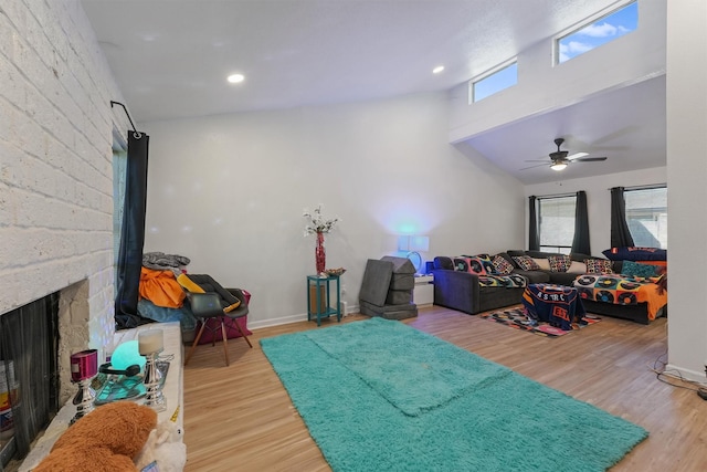 living area with a brick fireplace, recessed lighting, wood finished floors, and a high ceiling